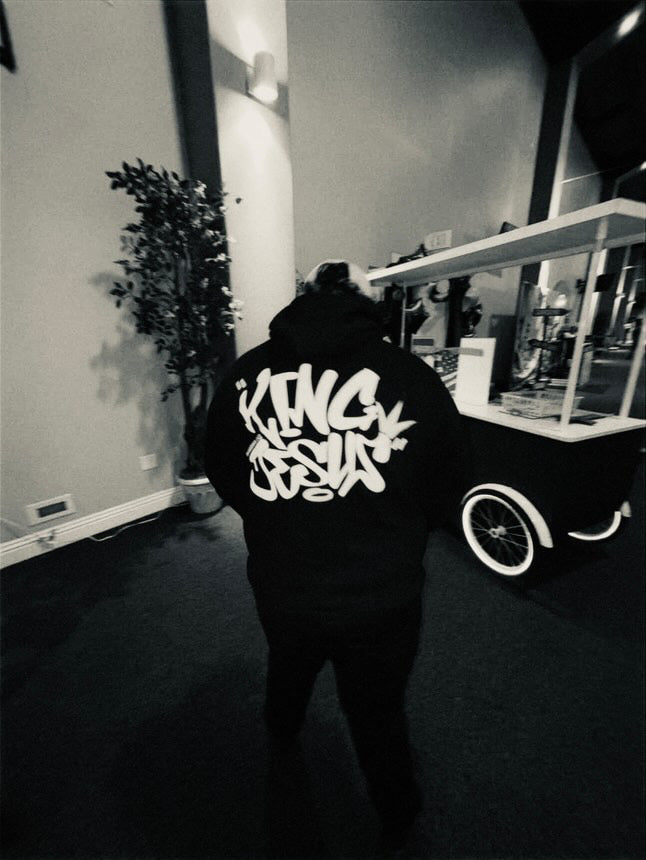 Filipino man displaying the back design of the King Jesus Hoodie from a side angle—Christian streetwear with a bold faith-inspired message.