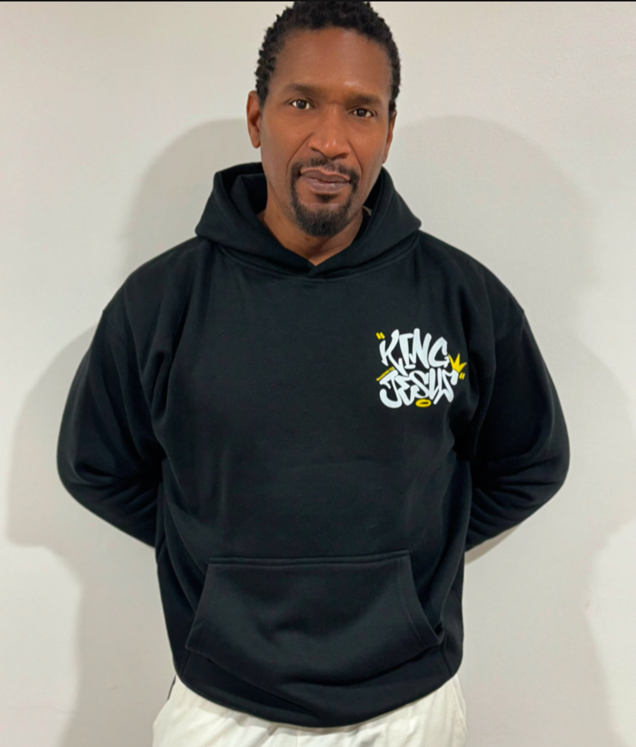 African American man posing with the King Jesus Hoodie, hands behind his back, showcasing bold Christian streetwear and faith-inspired fashion.